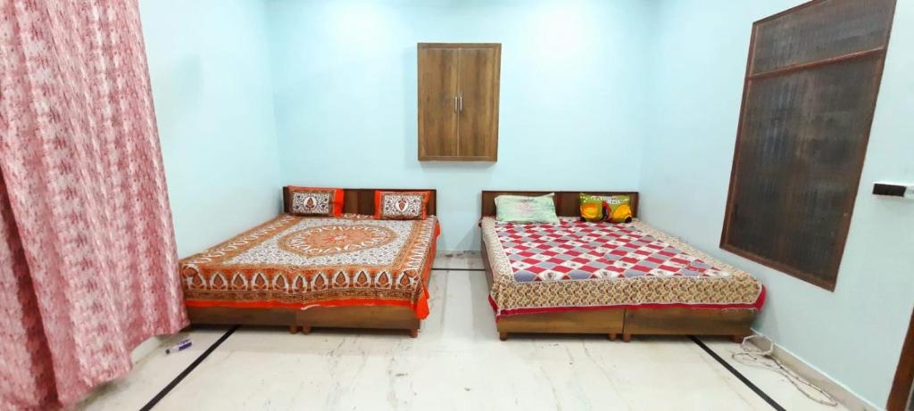 dos camas sentadas una al lado de la otra en una habitación en Nisha Homestay, en Aligarh
