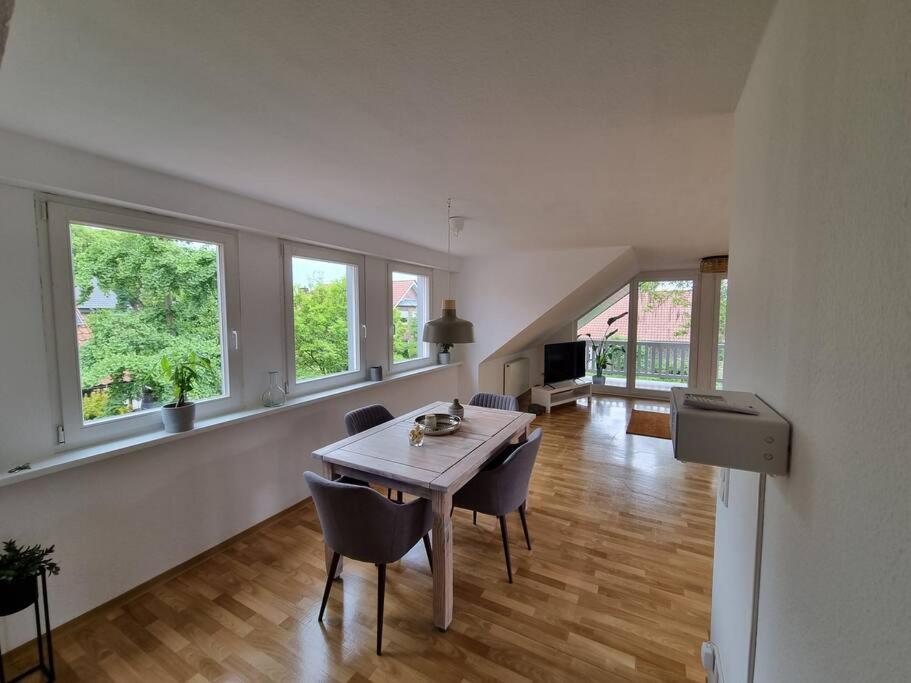 una sala da pranzo con tavolo, sedie e finestre di Schöne naturnahe und ruhige Wohnung a Telgte