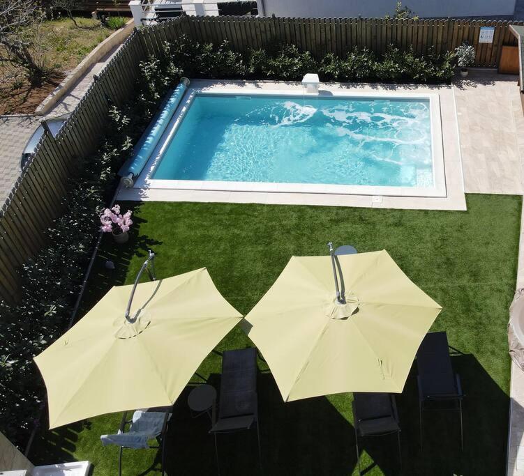 two umbrellas and chairs next to a swimming pool at Luxury Flat with Heated Pool & Jacuzzi in Rijeka