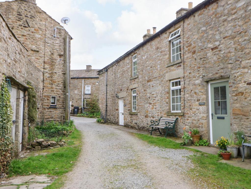 a dirt road between two stone buildings at Arklehurst in Low Eskcleth