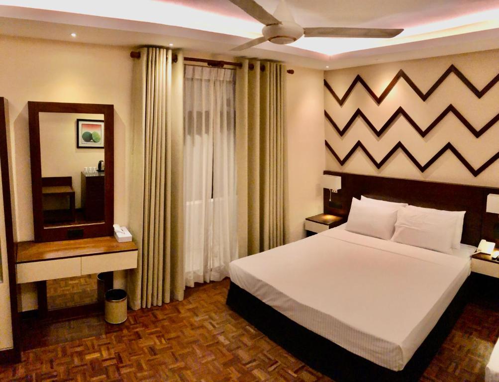 a bedroom with a large white bed and a mirror at Tropic Inn - Mount Lavinia in Watumulla