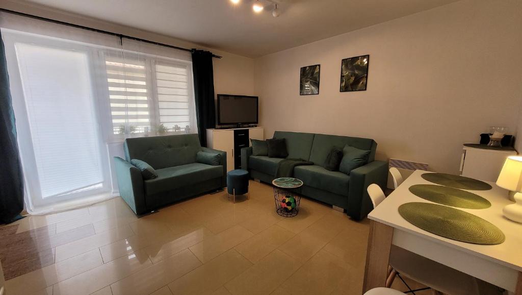 sala de estar con 2 sofás verdes y TV en Apartament Rybacka 84/7, en Krynica Morska