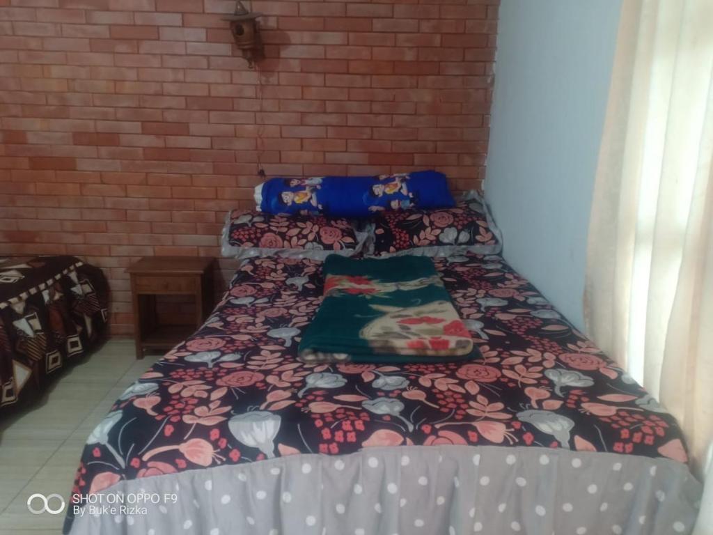 Un dormitorio con una cama con una manta. en Warung Rizka en Probolinggo