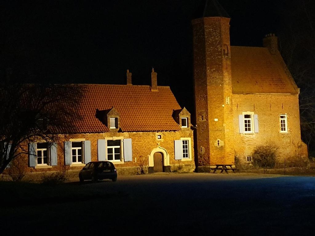 a large brick building with a tower at night at chambre aux tomettes au Major in Belle-et-Houllefort