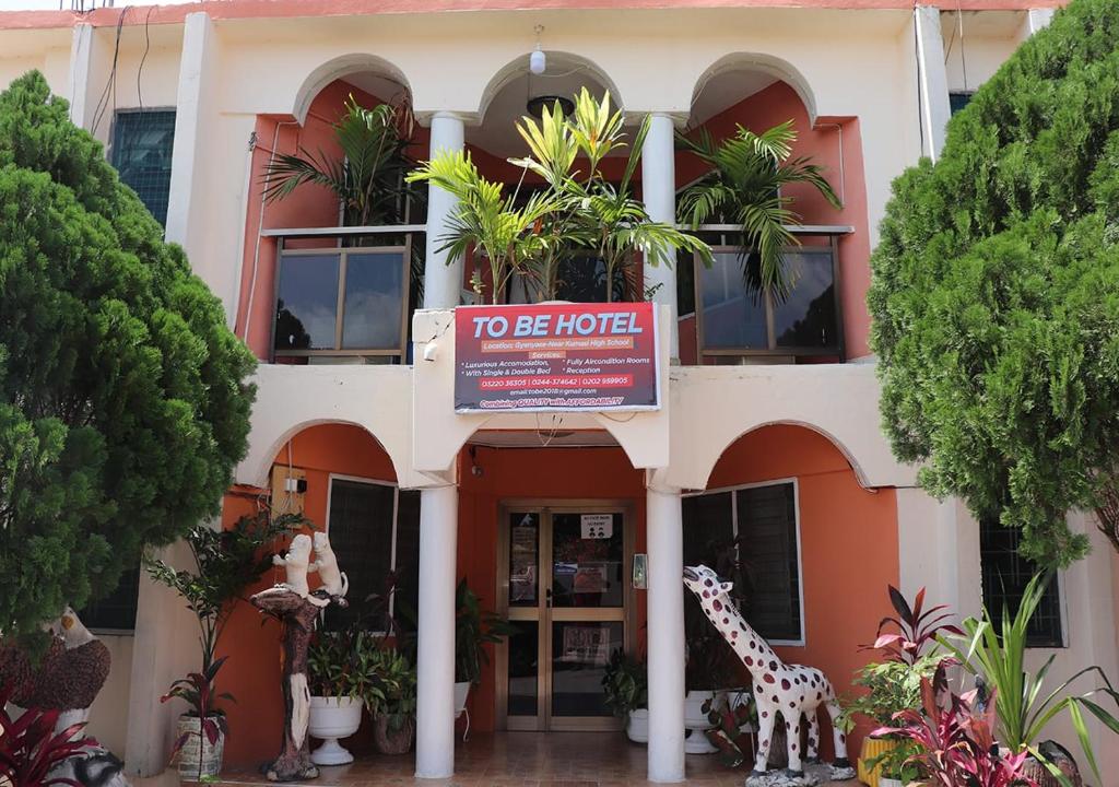 ein Gebäude mit einem Schild, auf dem steht, dass es sich um ein Hotel handelt in der Unterkunft To Be Hotel in Kumasi