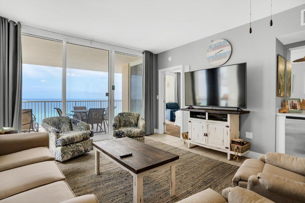 a living room with a television and a couch and chairs at Majestic Beach Towers 2-909 in Panama City Beach