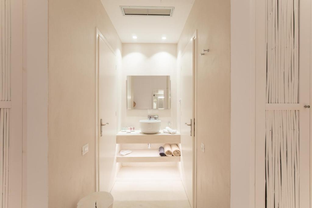 a white bathroom with a sink and a mirror at The Ammonite Resort in Super Paradise Beach