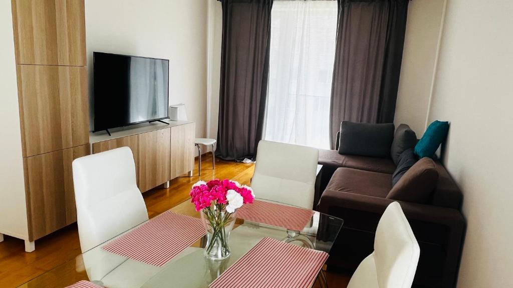 sala de estar con sofá y mesa con flores en Apartment Hurka - 15 min do centra, garaz, en Praga