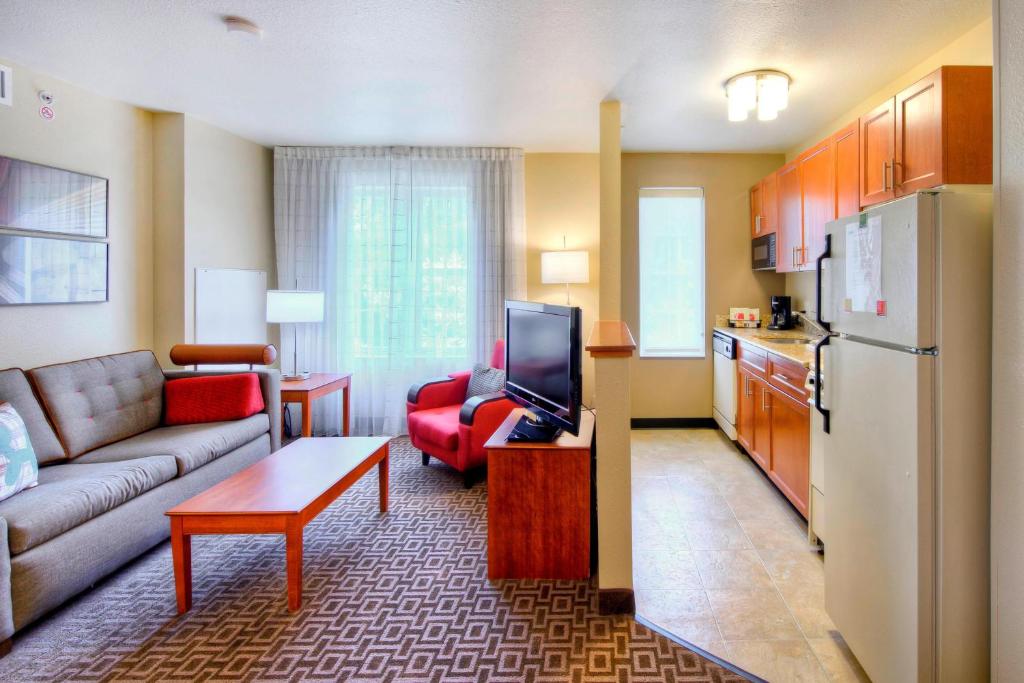 a living room with a couch and a tv and a kitchen at TownePlace Suites Raleigh Cary/Weston Parkway in Cary