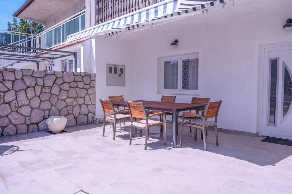 a table and chairs on a patio with a stone wall at Krasa Escape in Novi Vinodolski