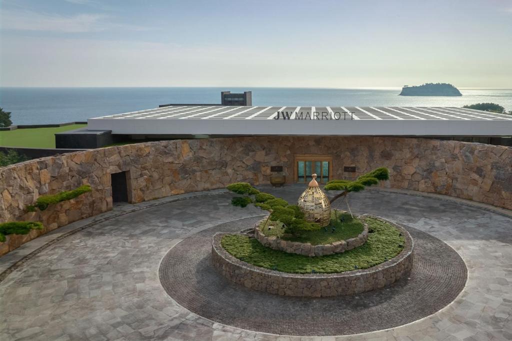 西歸浦的住宿－JW Marriott Jeju Resort & Spa，一座以海洋为背景的建筑前方的喷泉