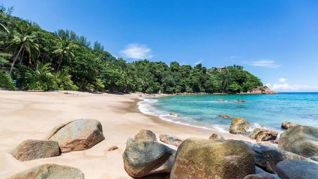 a beach with rocks in the sand and the ocean at Benetti house in Patong Beach