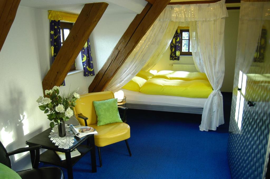 a bedroom with two beds and a yellow chair at Landhaus Sorgenfrei in Hohnstein
