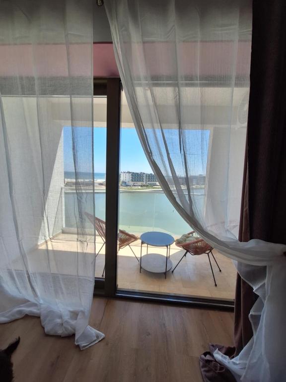 een kamer met een raam met uitzicht op het water bij Emmaia Sunrise Luxury Appartment in Eforie Nord