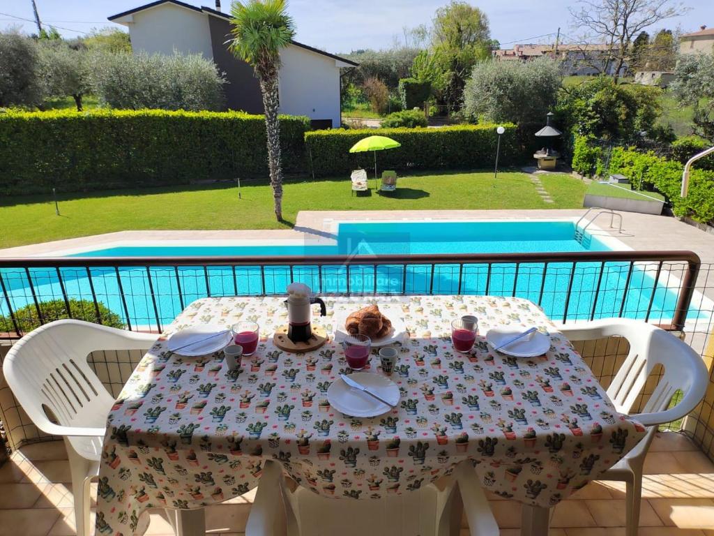 un tavolo con un piatto di cibo sopra accanto a una piscina di La Palma - Immobiliare Azzurra a Lazise