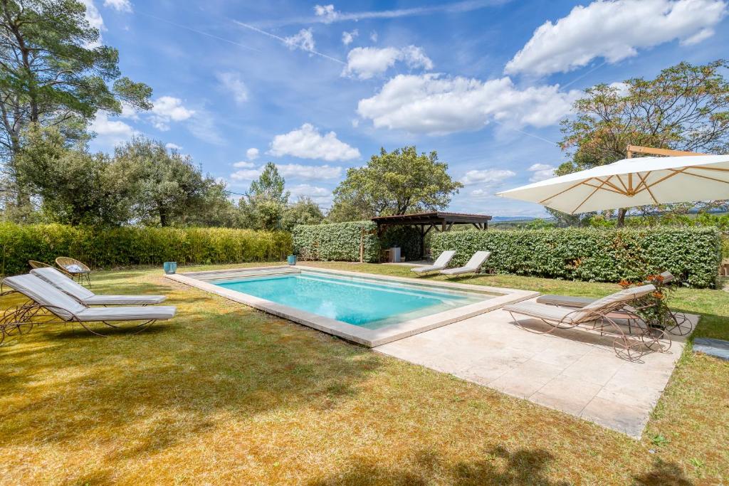 einen Pool mit zwei Liegestühlen und einem Sonnenschirm in der Unterkunft Villa des Roses à Lorgues in Lorgues