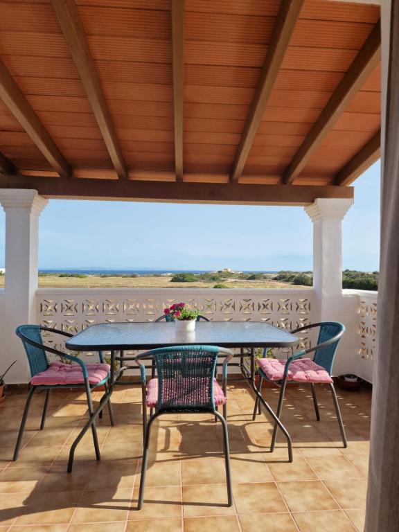 una mesa y sillas en un patio con vistas al océano en Viviendas Es Carnatge, Can Mestre en Playa de Migjorn