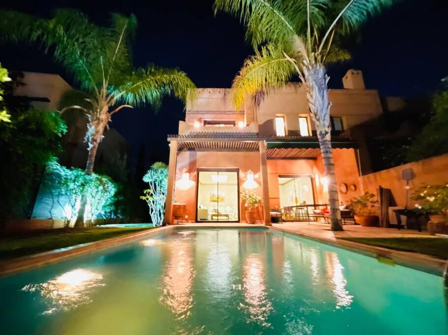 una piscina frente a una casa por la noche en Villa Hanaa sur golf piscine privée, en Marrakech