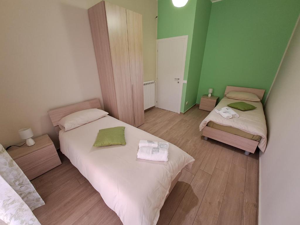 two beds in a room with green walls and wooden floors at La casa dei girasoli in Marsala