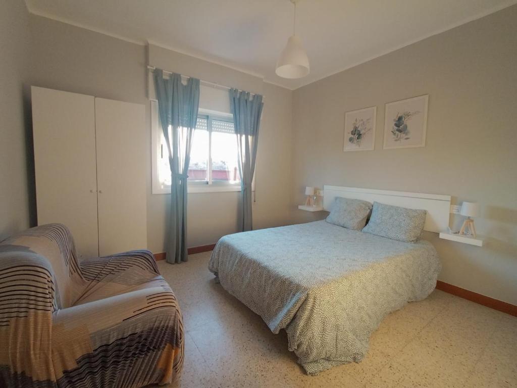 um quarto com uma cama e uma cadeira em Apartamento vacacional en Playa del Vao - Corujo em Vigo