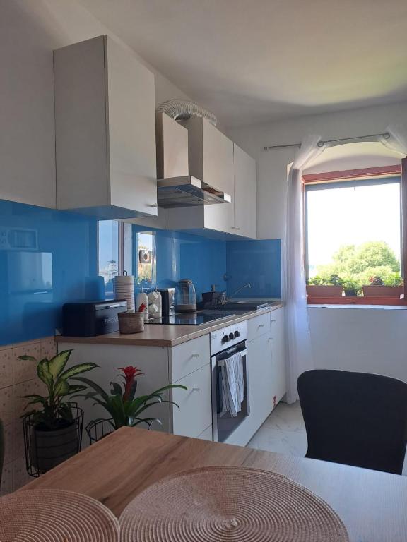 Una cocina con paredes azules y gabinetes blancos y una ventana. en Spalato, en Split