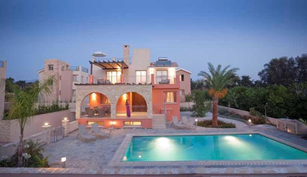 une grande maison avec une piscine en face de celle-ci dans l'établissement Villa Saraliana Sandy Beach Villas - Heated Pool - Jacuzzi - Private Beach Area, à Pólis Chrysochoús