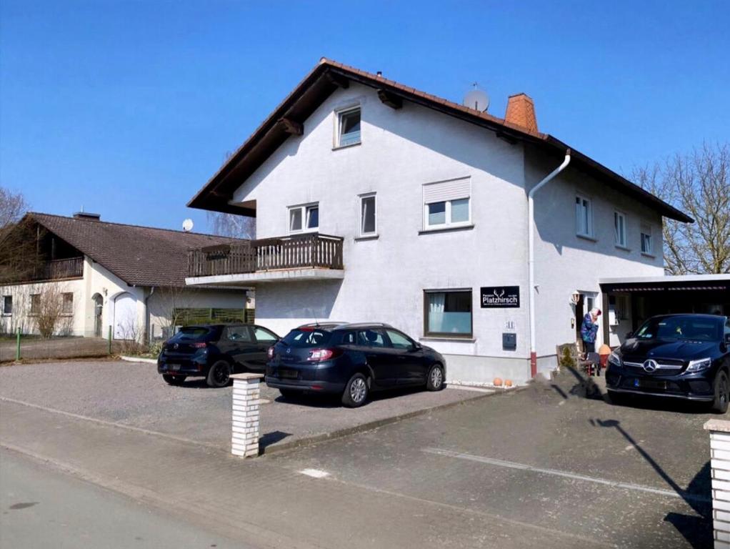 two cars parked in a parking lot in front of a house at Pension Platzhirsch in Mücke