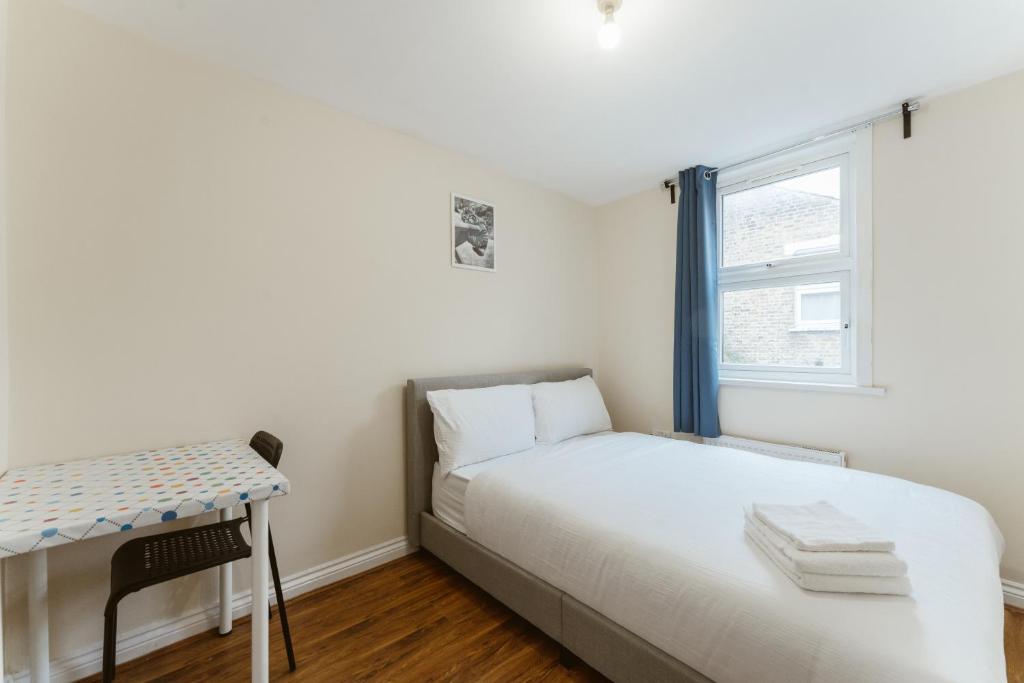 a bedroom with a bed and a desk and a window at Mile End Rooms 57A in London