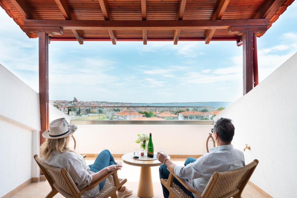 a couple sitting in chairs in front of a large window at EVERGREEN apartment in Nea Moudania