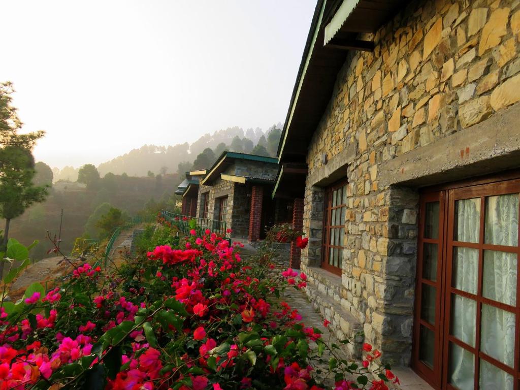 una casa de piedra con flores delante en Faraway Renz en Bhikia Sain