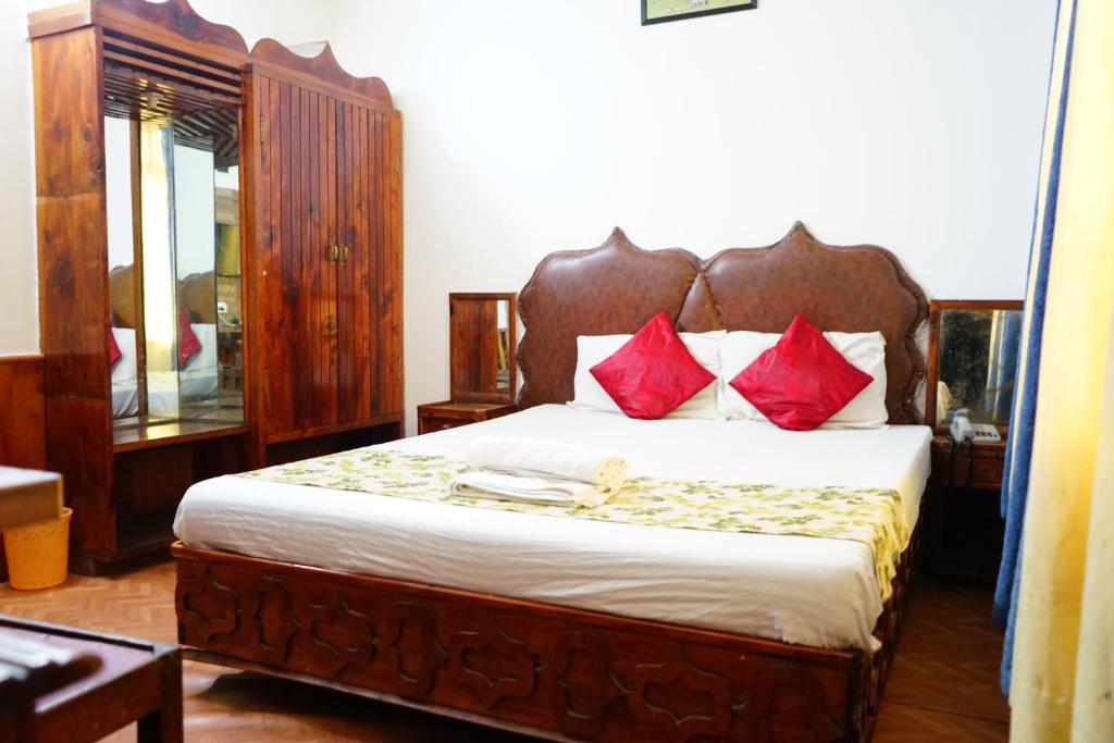 a bedroom with a large bed with red pillows at Hotel Magnolia Mallroad Manali in Manāli