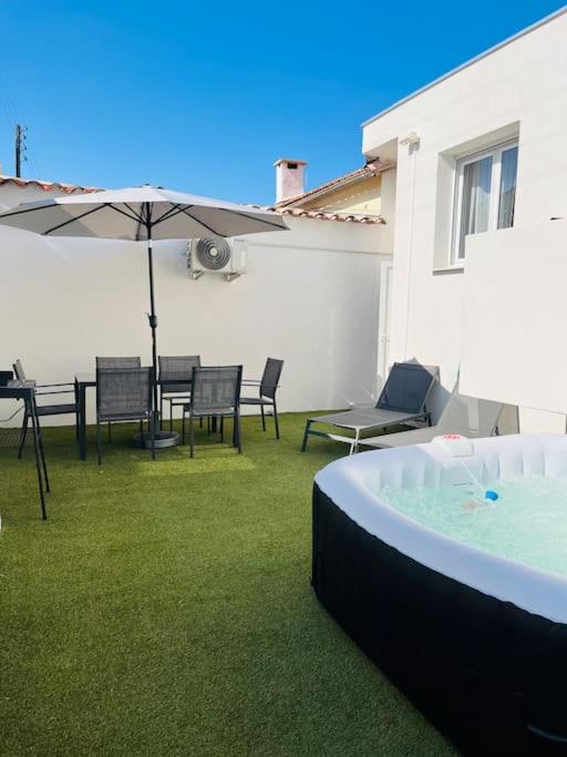 taras ze stołem, krzesłami i parasolem w obiekcie Maison 4 personnes avec jacuzzi w mieście Marignane