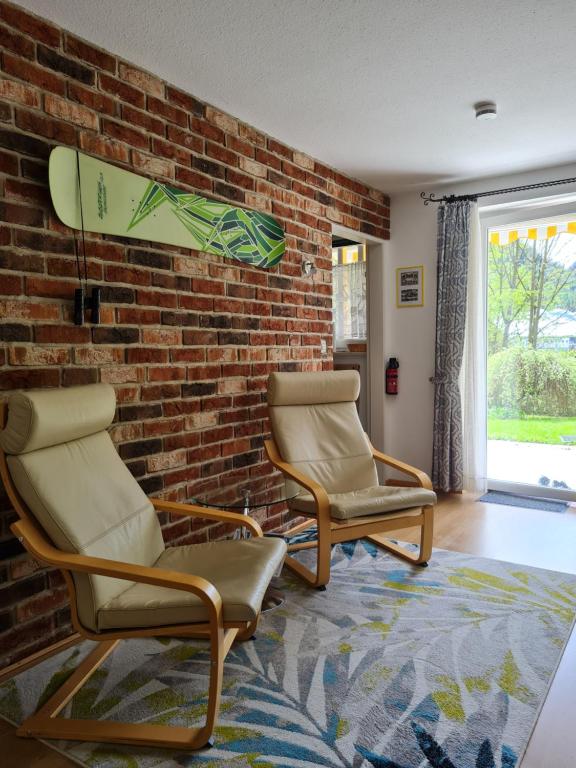 uma sala de estar com duas cadeiras e uma parede de tijolos em Ferienwohnung BerGlück em Inzell