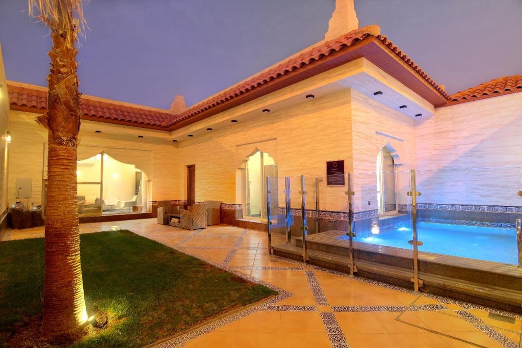 una casa con una piscina y una palmera en شاليهات أندلوسيا en Riad
