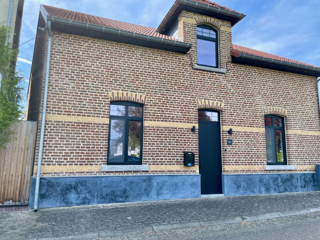 uma casa de tijolos com uma porta azul numa rua em Vakantiewoningen Bienvenue, Le Pont em Lanaken