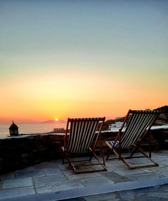 two chairs sitting on a patio watching the sunset at Aegean living Villa in Agios Romanos