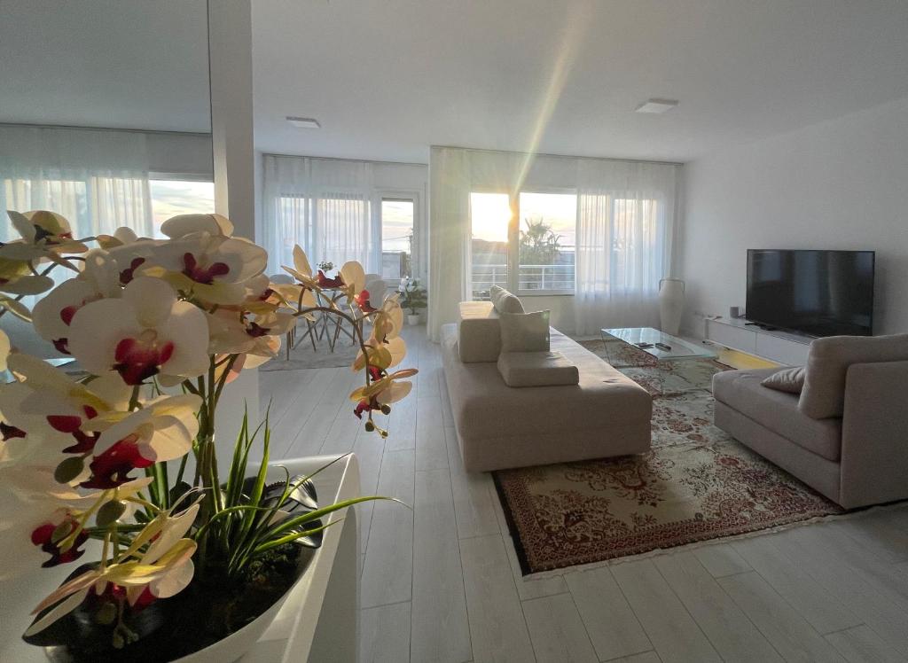 uma sala de estar com sofás e uma televisão e flores em Durres Currila SUNSET Beach Beaty em Durrës