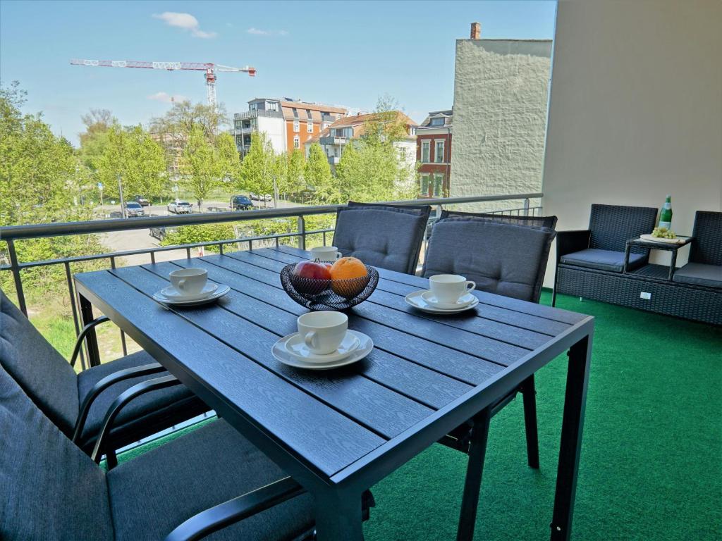 uma mesa de madeira com uma tigela de fruta na varanda em "HOGULU" Brandenburg, Balkon, Neustadt, Küche, Wassernähe - Parkplatz inklusive em Brandenburg an der Havel