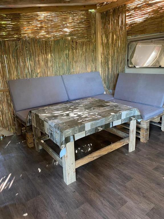 a wooden bench with a table in an old trailer at Delightful Beach & Forest Caravan in Chernomorets