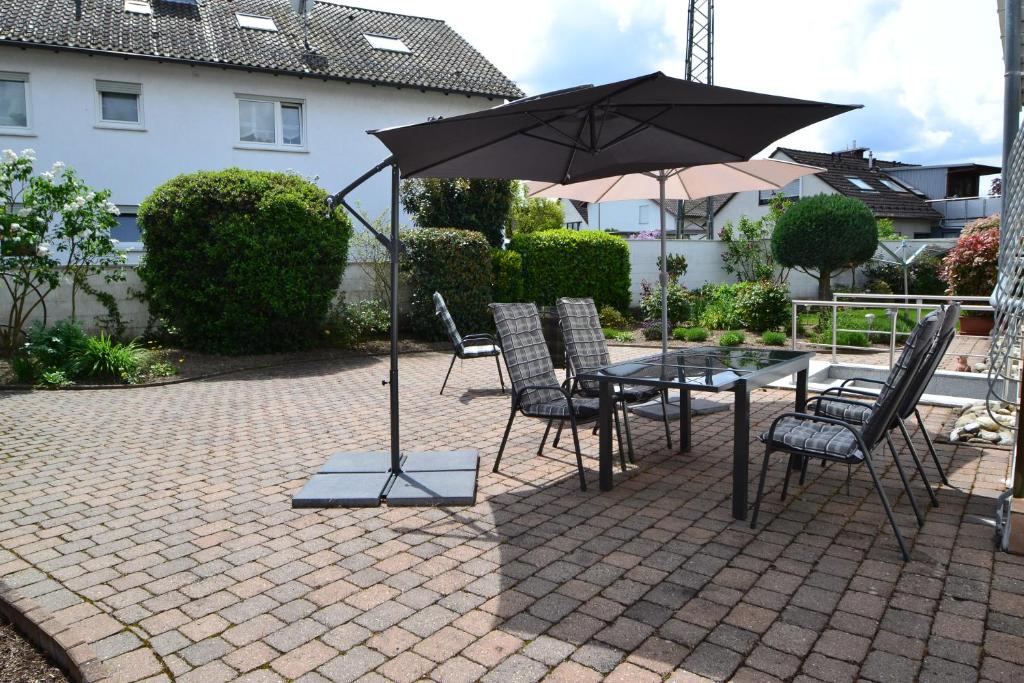 un patio con mesa, sillas y sombrilla en Zauber der Pfalz en Römerberg