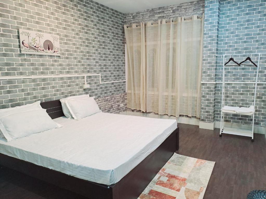 ein Schlafzimmer mit einem Bett und einer Ziegelwand in der Unterkunft Strawberry Swing Homestay in Guwahati