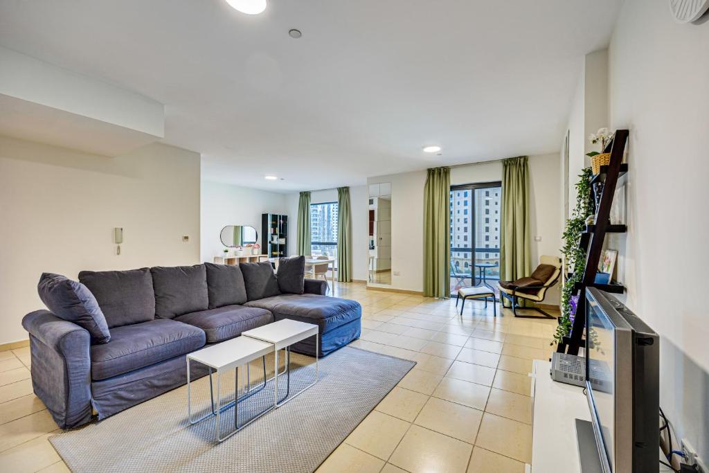 a living room with a blue couch and a tv at Big Apartment in Murjan, JBR, near the beach in Dubai