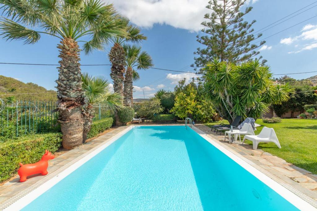 a swimming pool in a yard with palm trees at Iliachtida House in Sounio