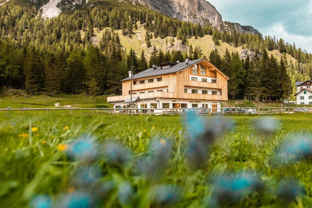 a large wooden house in a field with flowers at Chalet Alpenrose in Misurina
