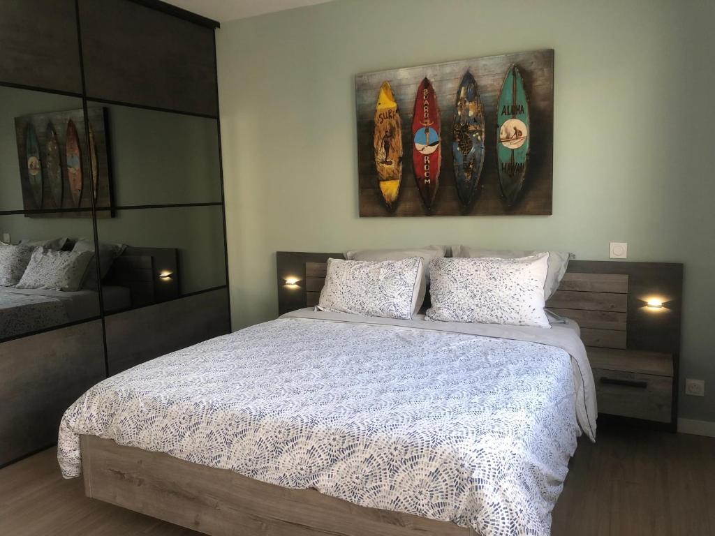 1 dormitorio con 1 cama y pinturas de barcos en la pared en Studio au calme, coeur d’Arradon, en Arradon