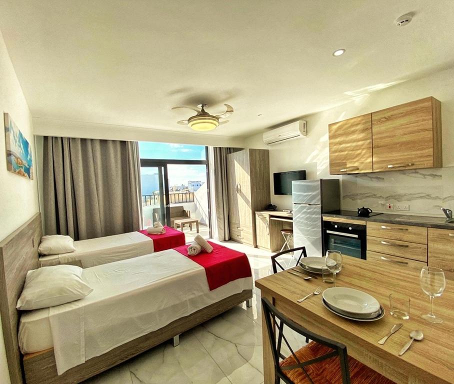 Habitación de hotel con cama, mesa y cocina en For Rest Aparthotel, en St Paul's Bay
