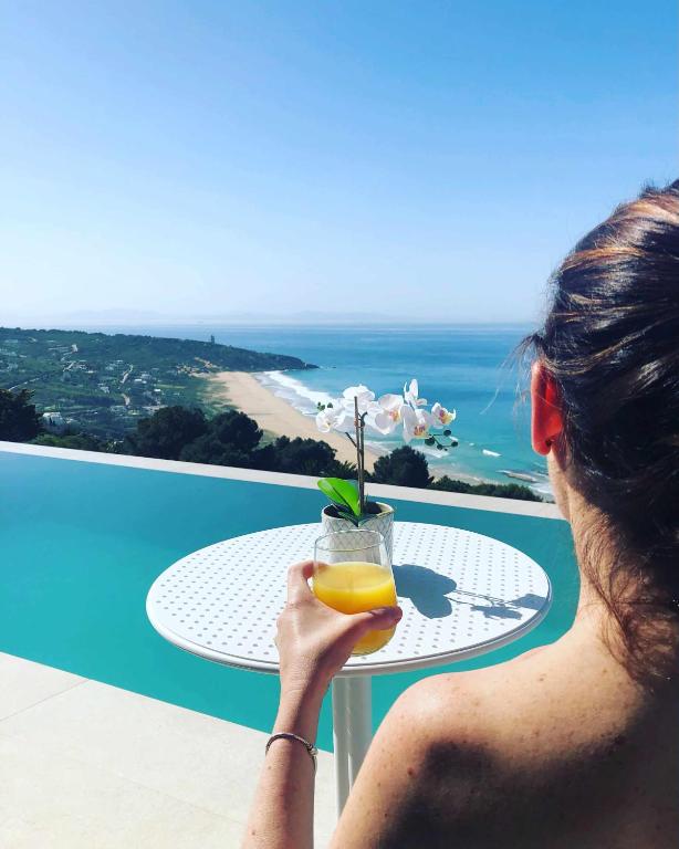 a woman is holding a glass of orange juice at Villa El Buzo in Zahara de los Atunes