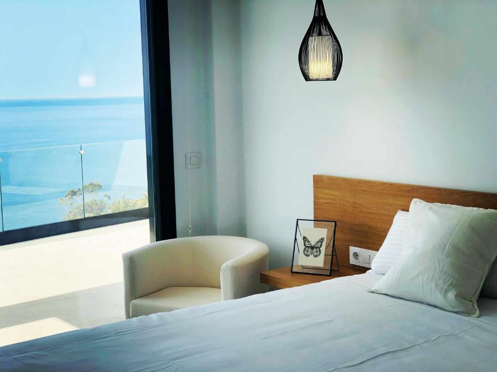 a bedroom with a bed and a chair and a window at Villa El Buzo in Zahara de los Atunes