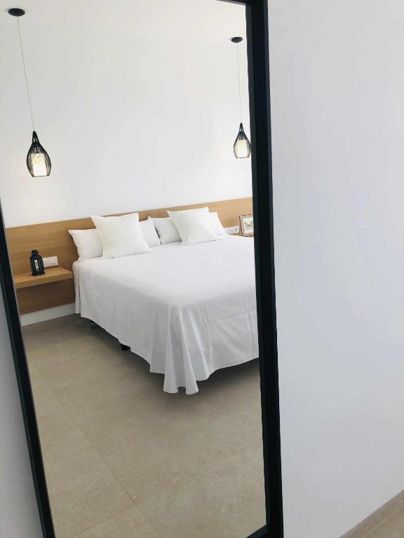 a bedroom with a white bed and a mirror at Villa El Buzo in Zahara de los Atunes