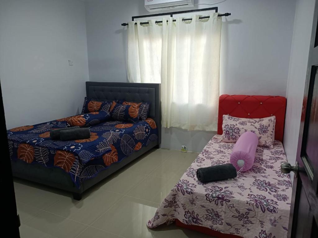 a bedroom with a bed and a bed and a couch at RIANI HOMESTAY in Kertih